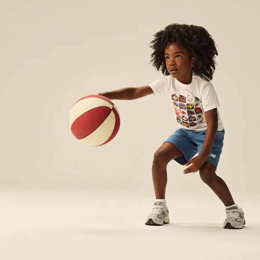 Child holding a basketball on a plain background